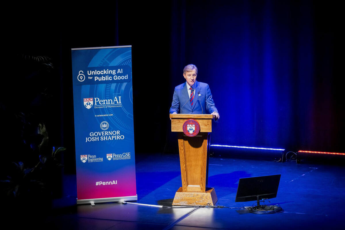 Penn President J. Larry Jameson on stage at the podium next to a banner that reads “Unlocking AI for Public Good.”