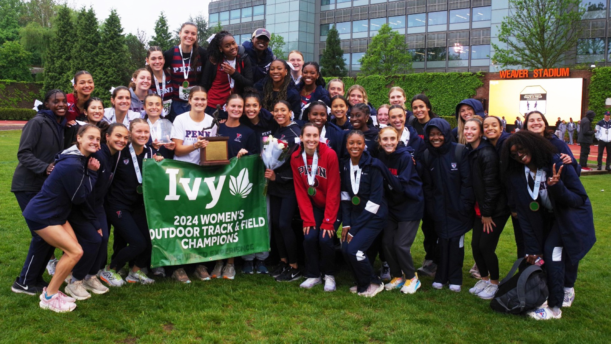 Members of the women's track and field team pose with the championship banner.